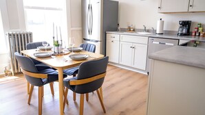 Cocina moderna con refrigerador, estufa y pileta. Hay una mesa de comedor con sillas y un ventanal que proporciona luz natural.
