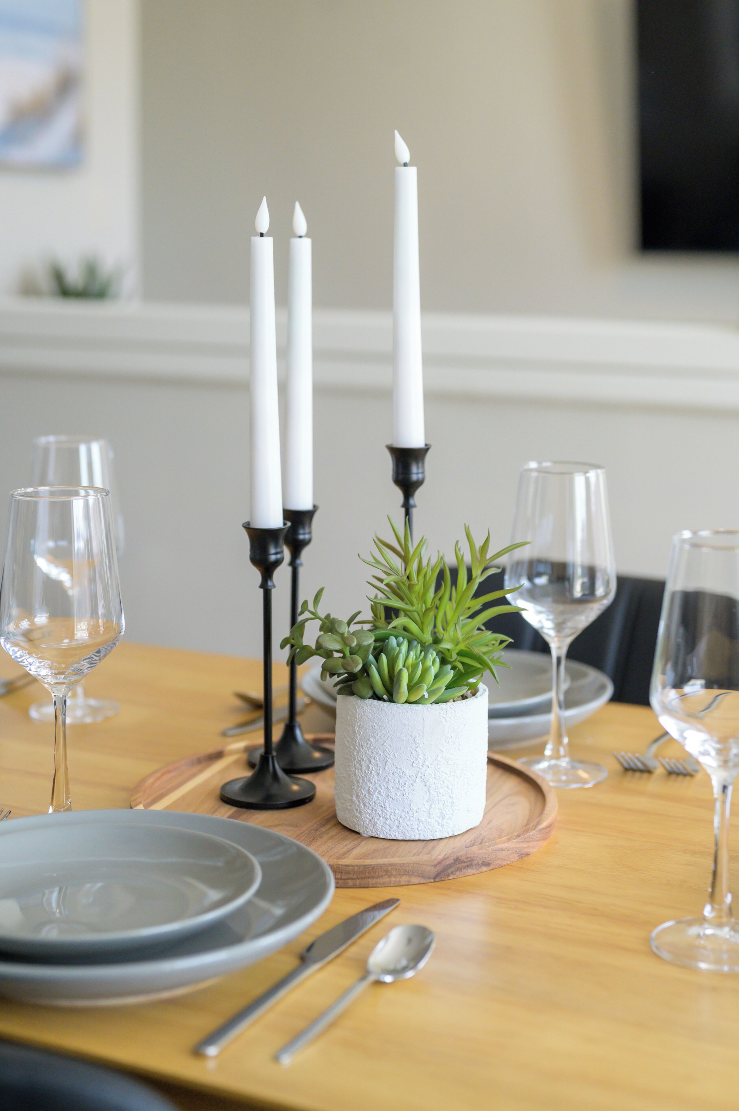 A dining table set with plates, cutlery, glasses, and candles.