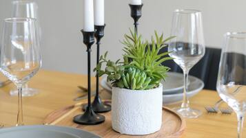 A dining table set with plates, cutlery, glasses, and candles.