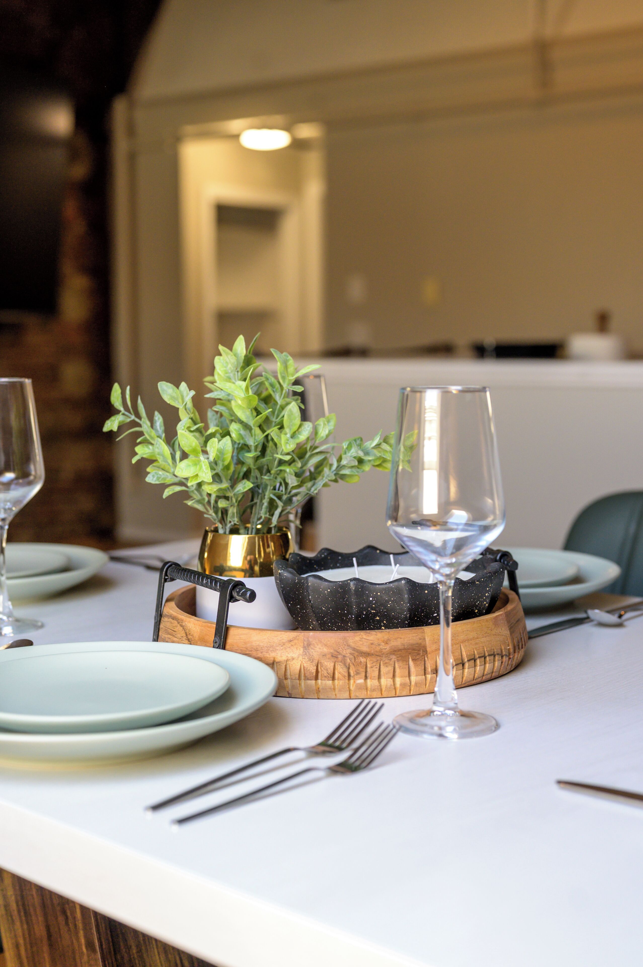 Une table à manger avec une plante, un verre à vin et des couverts.