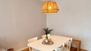 En matplats med ett runt bord, sex stolar, en hängande lampa och en liten växt på bordet.