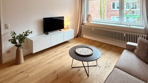 Ett modernt vardagsrum med en TV, en vit TV-bänk, ett runt soffbord och en soffa.