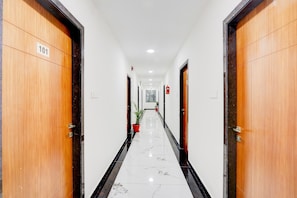 A hallway with wooden doors, numbered 101, leading to a room. - Super Townhouse Oak Garden (Hanmakonda)