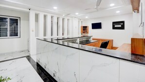 A modern reception area with a marble counter, ceiling fans, and a sign indicating 'TOWNHOUSE OAK & Company Serviced'. - Super Townhouse Oak Garden (Hanmakonda)