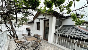 A balcony with a tiled floor, a wooden table with chairs, and a white railing.