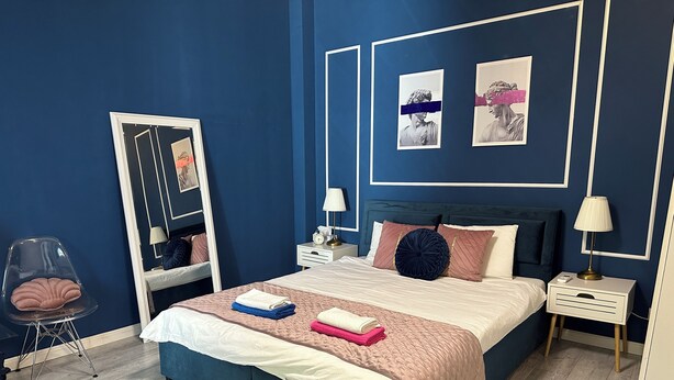 A bedroom with a bed, bedside tables, a mirror, and a chair.