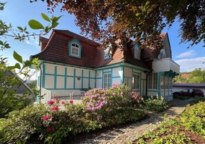 Ein traditionelles Fachwerkhäuschen mit Garten und einem roten Auto vor der Tür.