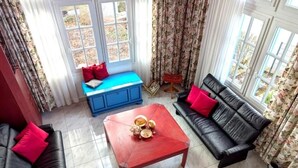 En stue med en blå bænk, et rødt sofabord og en sort lædersofa.