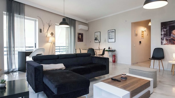 A modern living room with a sectional sofa, a coffee table, and a dining area with chairs.
