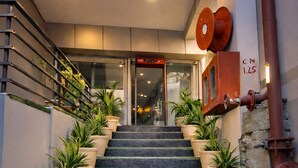 Una escalera con plantas en macetas, una barandilla de metal y una puerta con un letrero encima.