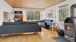 Moderni olohuone, jossa on sohva, ruokapöytä ja puuhella.