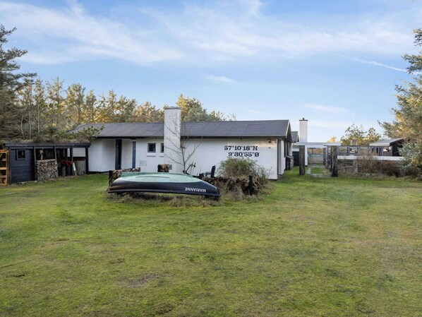 A house with a white exterior, a black roof, and a chimney. There is a green inflatable raft in front of the house. - 4 Star Holiday Home in Lokken (Lokken)