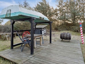 Eine Holzterrasse mit einer rustikalen Holzhütte, einem Fass und einem roten und weißen Streifenmast.