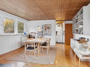 Eine moderne Küche mit weißen Schränken, einer Holzbalkendecke und einem Essbereich mit Tisch und Stühlen.