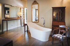 A bathroom with a freestanding bathtub, a wooden chair, a vanity with a mirror, and a cabinet. - TENUTA LISETTA (Monterotondo)