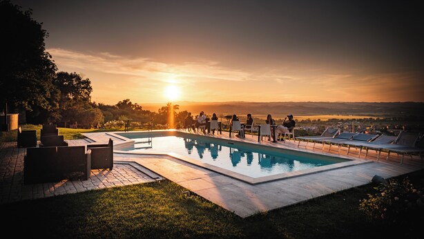 A swimming pool with lounge chairs and a view of the sunset. - TENUTA LISETTA (Monterotondo)