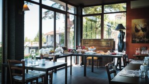 A dining area with large windows, wooden furniture, and a view of the outside. - TENUTA LISETTA (Monterotondo)