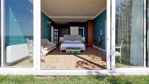A bedroom with a bed, bedside tables, a sofa, a small table, and a view of the ocean. - TENUTA LISETTA (Monterotondo)