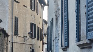 Una stretta strada acciottolata affiancata da edifici storici con persiane e un balcone in metallo.