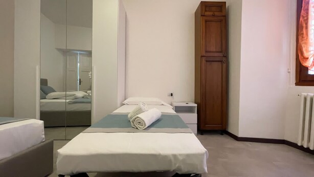 Una camera da letto con un letto, un armadio in legno, un comodino e uno specchio.