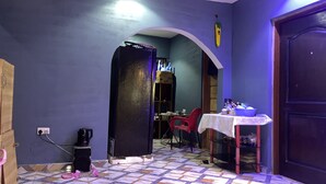 A room with a tiled floor, a table with a tablecloth, a red chair, and a closed door.
