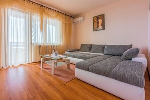 A living room with a sofa, a glass coffee table, and sheer curtains. - Apartment with balcony, sea view and fitness room (Crikvenica)