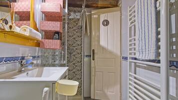 Un baño con lavamanos, espejo y toallero.