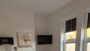 A bedroom with a bed, a bedside table with a tray of breakfast, a microwave, a TV, and a window with blinds. - Contemporary City Studio 1 - Contractor's and traveller's accommodation (Peterborough)