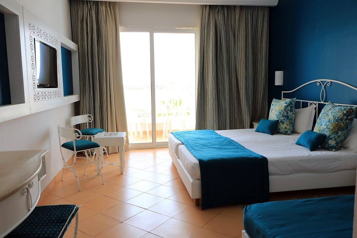 A hotel room with a bed, a desk, a chair, and a TV.