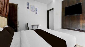 A modern hotel room with a large bed, a flat-screen TV mounted on the wall, and a small table. - Deluxe Townhouse Pimple Nilakh Pune (Pune)
