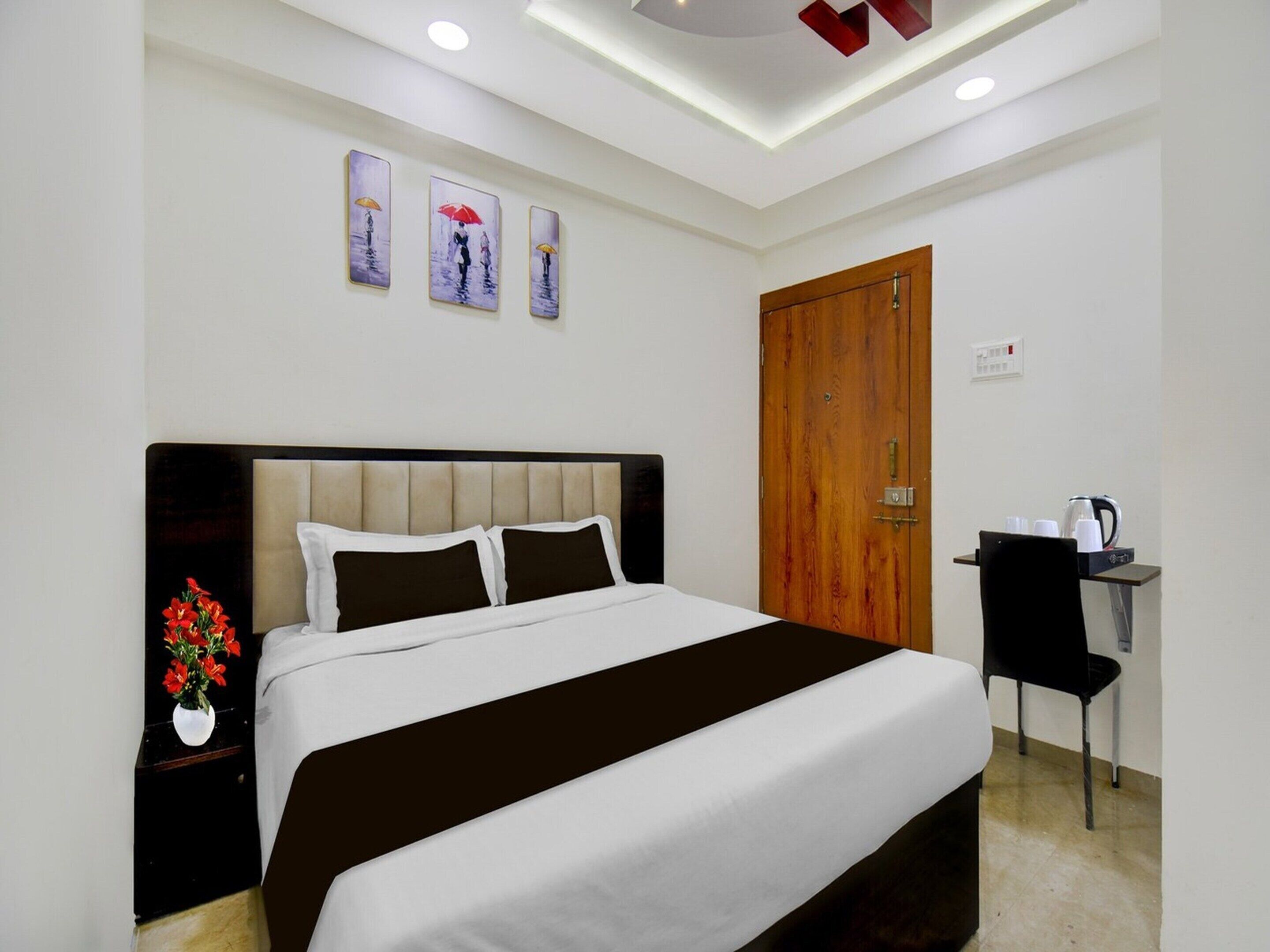 A hotel room with a bed, a desk, a chair, and a wooden door.