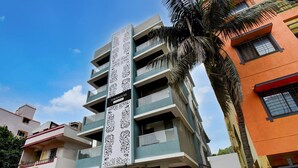A multi-story building with a vertical decorative panel, balconies, and a palm tree. - Deluxe Townhouse Pimple Nilakh Pune (Pune)