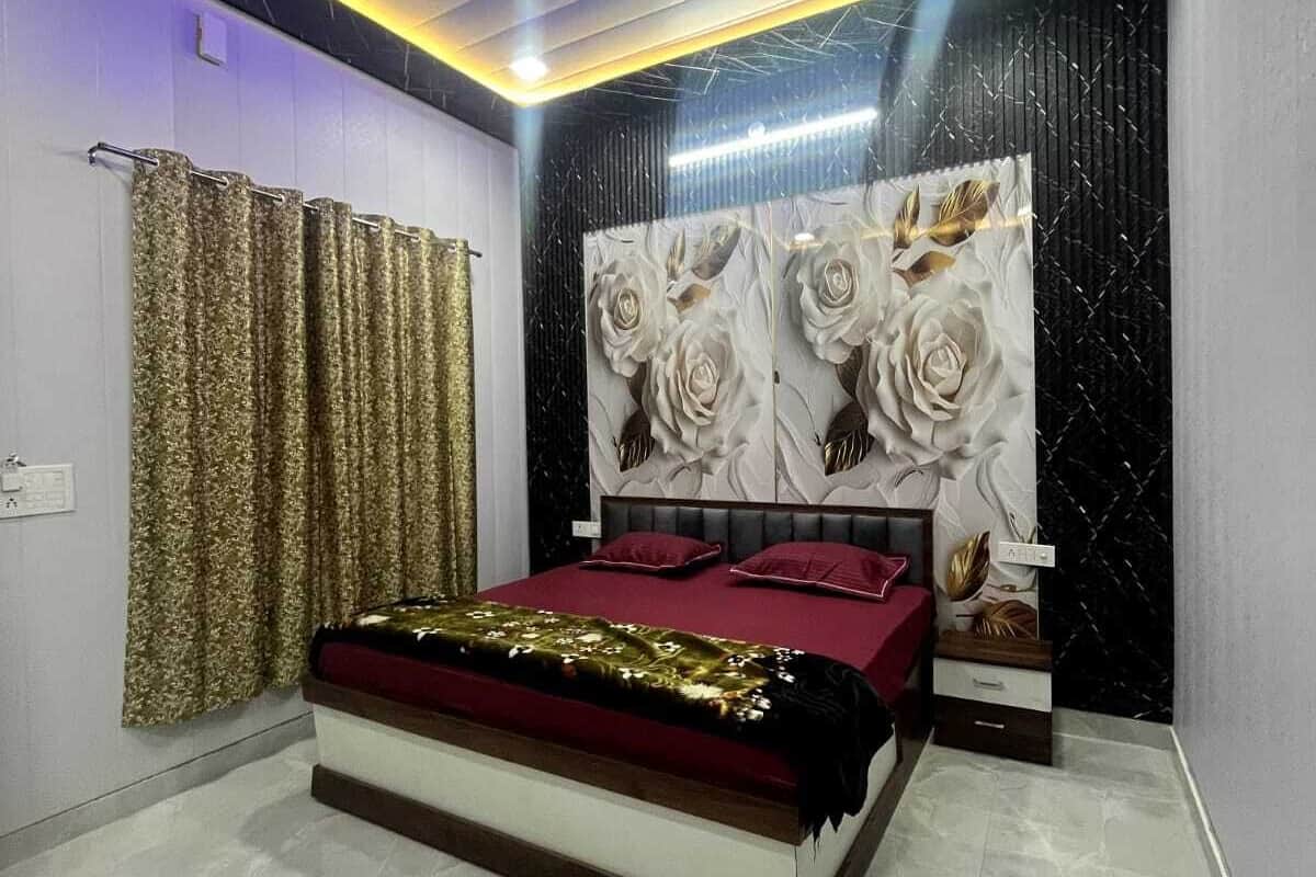 Un dormitorio con cama, una pared con un mural floral, iluminación geométrica en el techo y una cortina.