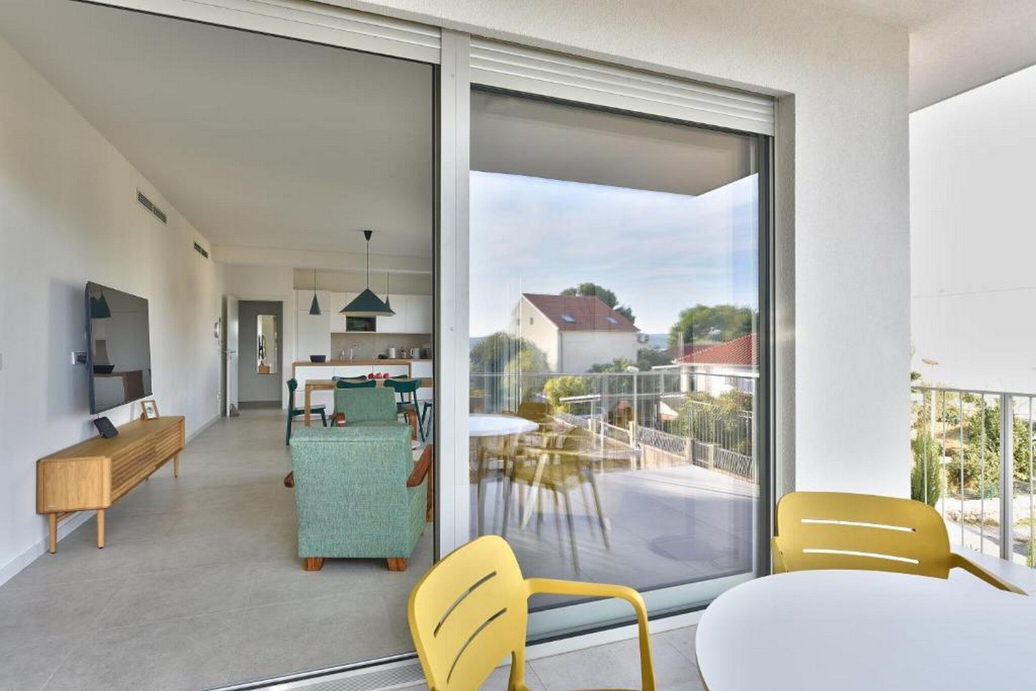 A modern apartment with a balcony, a dining area, and a kitchen.