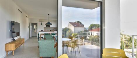 A modern apartment with a balcony, a dining area, and a kitchen.
