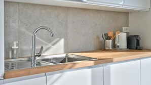 A modern kitchen with a stainless steel sink, a wooden countertop, and a coffee machine. - Apartment Recreation apt 3 (Sibenik)