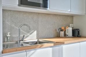 Eine moderne Küche mit Spüle aus Edelstahl, einer Holz Arbeitsplatte und einer Kaffeemaschine.