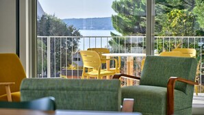 A balcony with yellow chairs and a green sofa, overlooking a lake and greenery. - Apartment Recreation apt 3 (Sibenik)