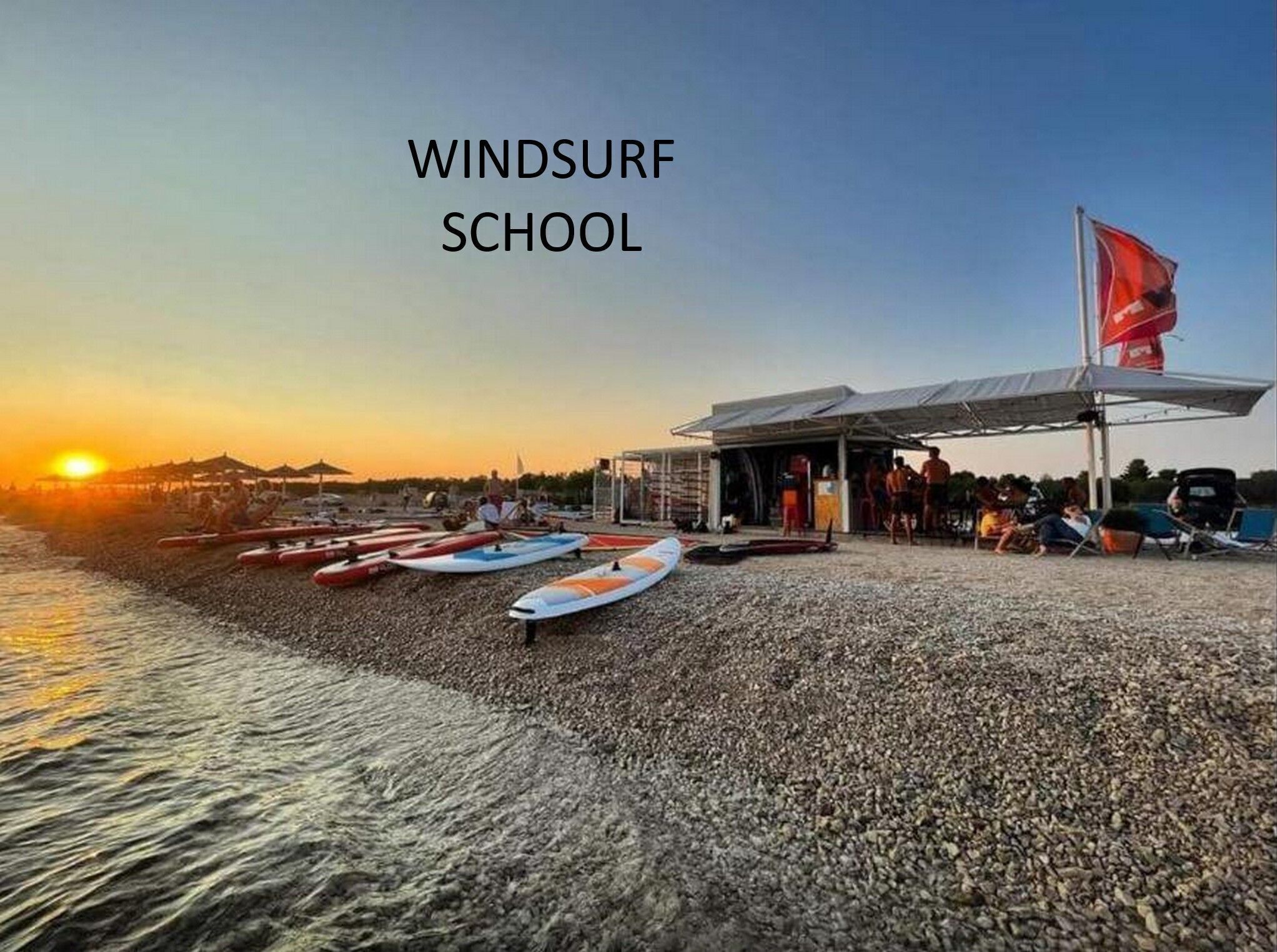 A windsurfing school with a covered seating area and multiple windsurfing boards.