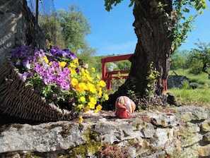 Mur de pedra amb una cistella de flors teixides i una estructura vermella.