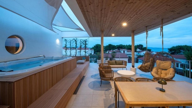 Una terrazza sul tetto con vasca idromassaggio, zona salotto e poltrone a dondolo.