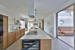 A modern kitchen with a central island, wooden cabinets, and a view to an outdoor deck. - Apartment Recreation Apt4 (Sibenik)