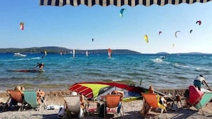Una spiaggia con persone che prendono il sole e praticano paracadutismo ascensionale.