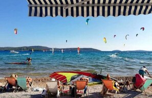 A beach with people sunbathing and parasailing. - Apartment Recreation Apt4 (Sibenik)