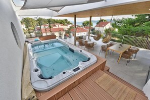 A hot tub on a balcony with wicker furniture and a view of houses. - Apartment Recreation Apt4 (Sibenik)