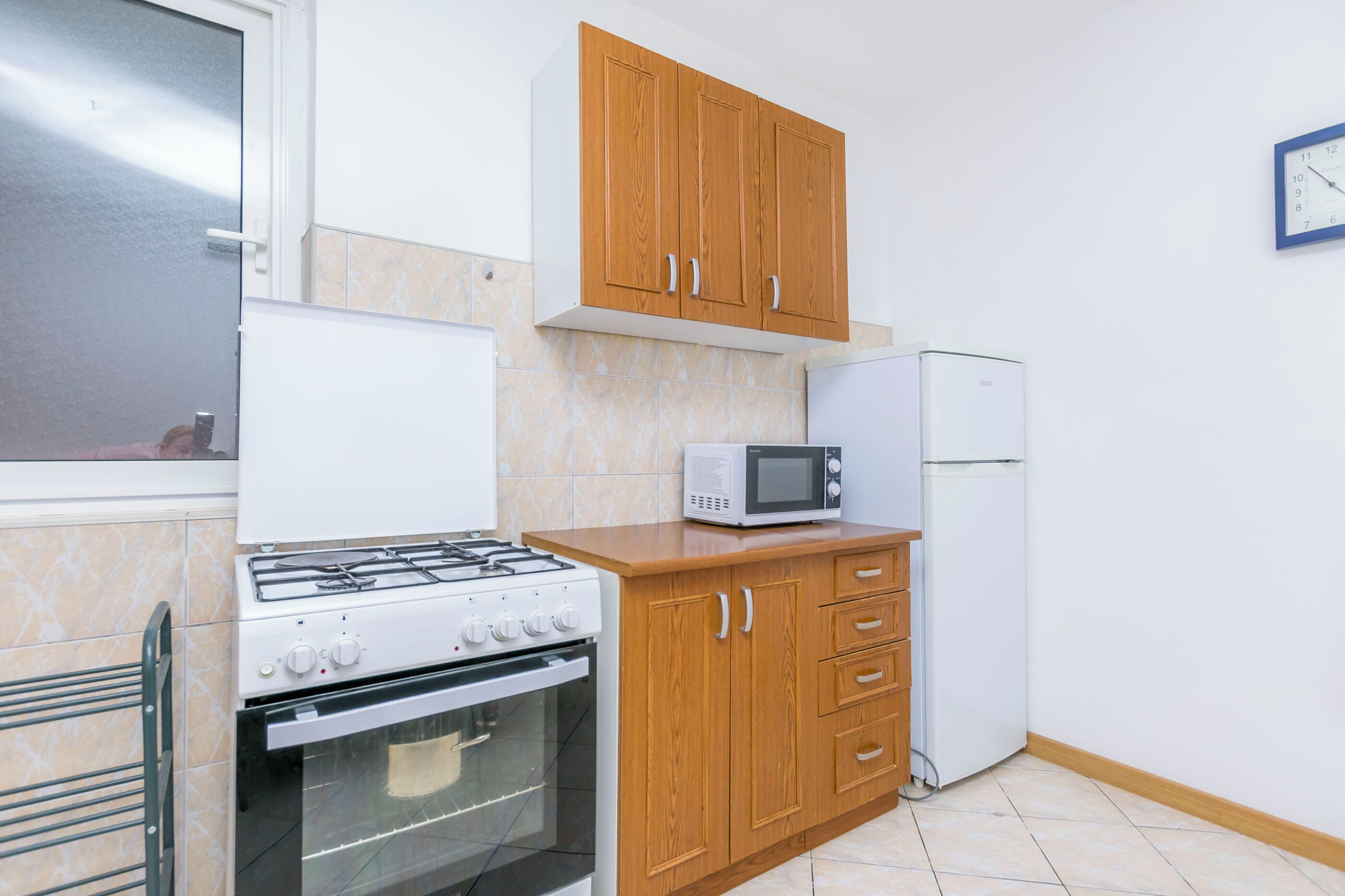A kitchen with wooden cabinets, a microwave, a refrigerator, a gas stove, and an oven.