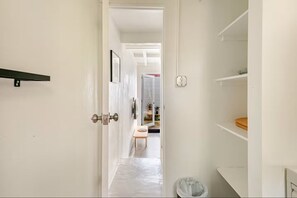 A hallway with a door, a small table, and a trash bin. - Lealtad-Santurce Secret Garden Loft (San Juan)