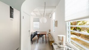 Uma cozinha moderna com área de refeições, uma geladeira branca, uma cafeteira e uma janela com vista para o exterior.