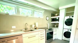 Una cocina moderna con electrodomésticos de acero inoxidable, lavavajillas, horno y lavadora integrada.