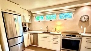 Una cocina moderna con electrodomésticos de acero inoxidable, lavavajillas, horno doble y ventana con vistas.